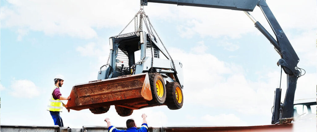 A bulldozer is lifted by a crane for transportation