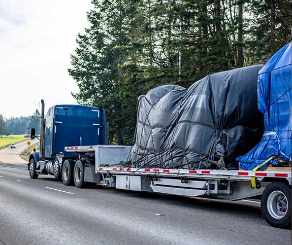 Flatbed trailer with a tarped load traveling down the Highway