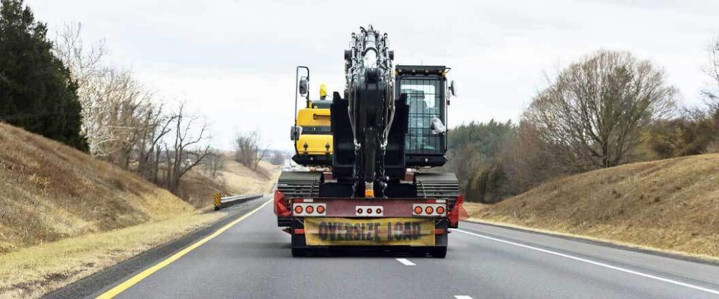 A semi truck transporting a a tractor on a lowboy trailer