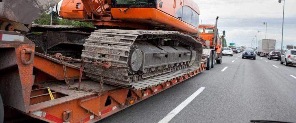 excavator being transported down a busy highway