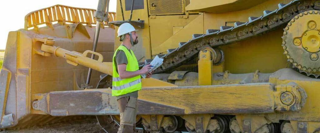 A construction worker examining a bulldozer