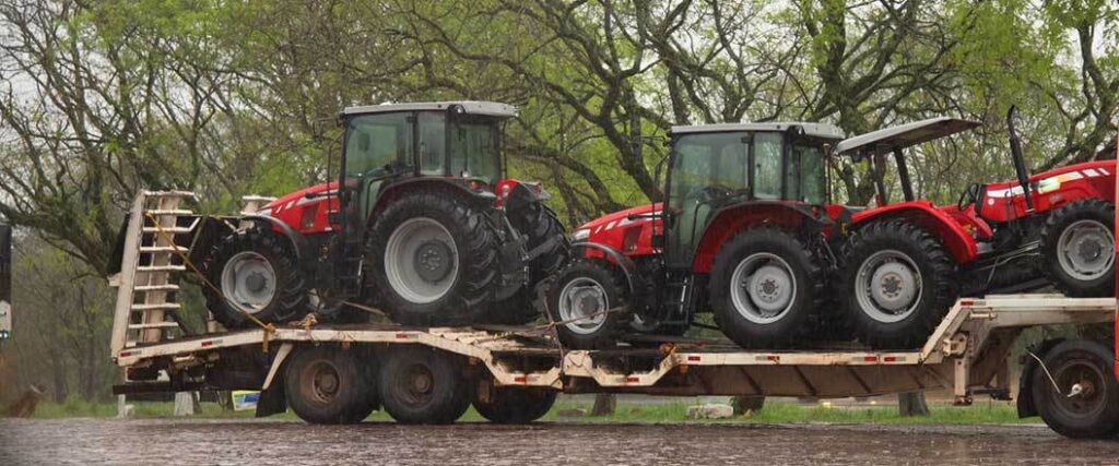 multiple tractors being hauled on a low boy trailer